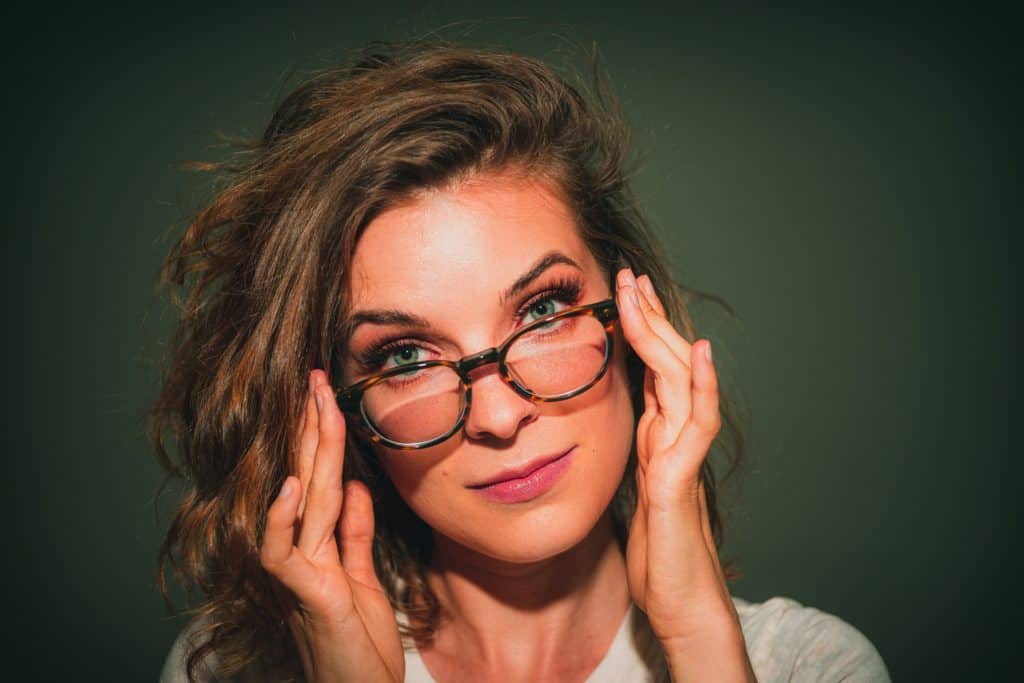 attractive nerdy woman pushing her glasses up onto her face